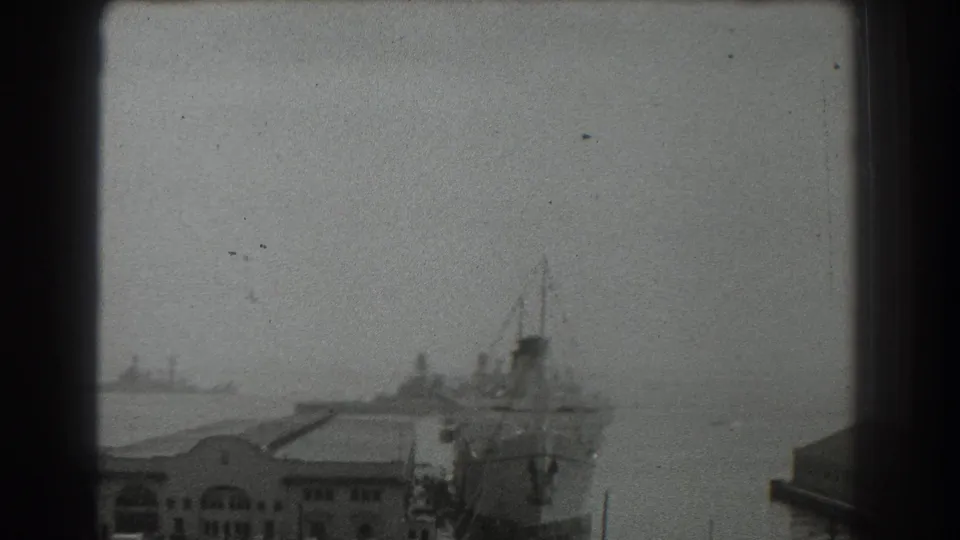 1939 San Francisco port scene showing a large docked vessel, low waterfront buildings, and another ship in the distance.