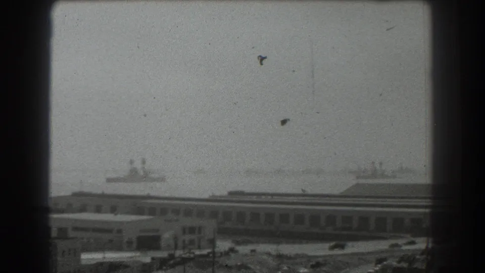 1939 San Francisco waterfront view with industrial buildings, cars, and distant ships framed by a dark window edge.