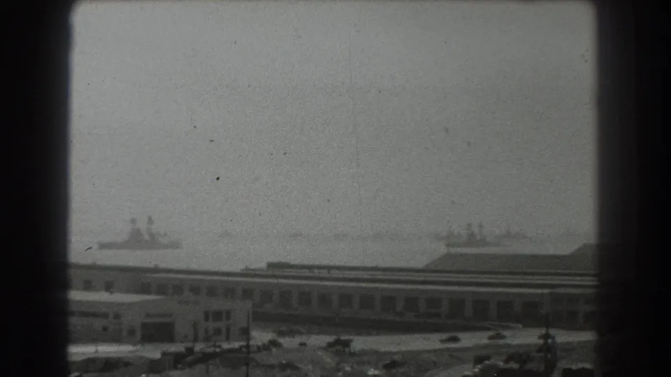 Soft 8mm view of San Francisco waterfront buildings and ships in the harbor distance, partially framed by dark borders.