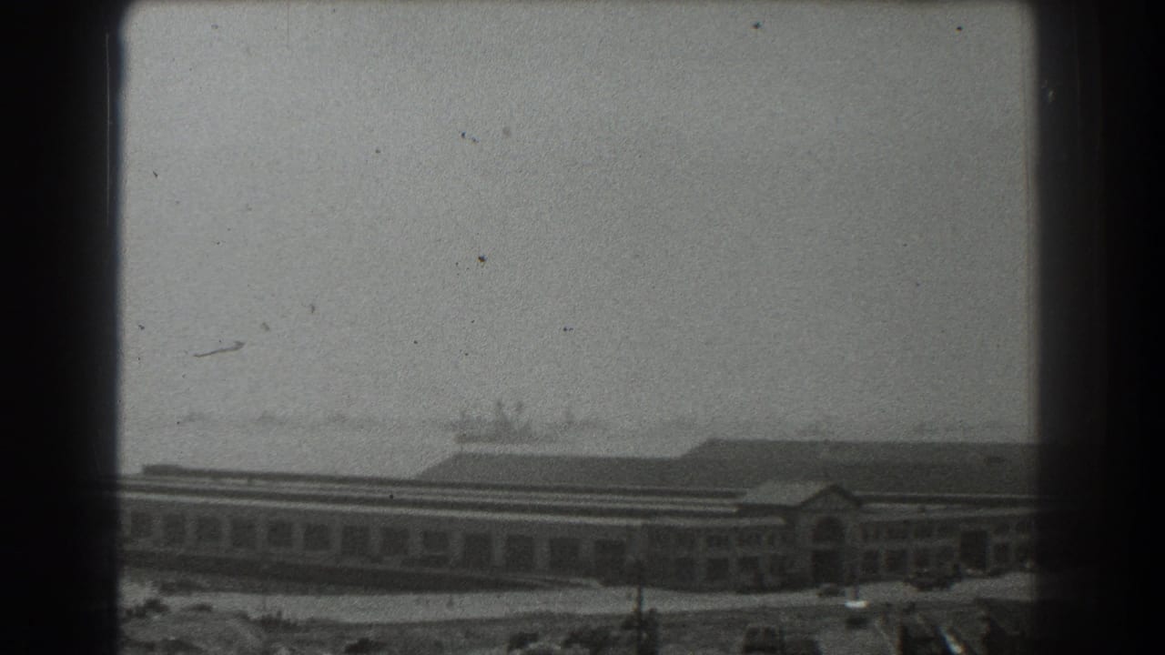 Waterfront building seen through dark film-frame edges with hazy harbor beyond.