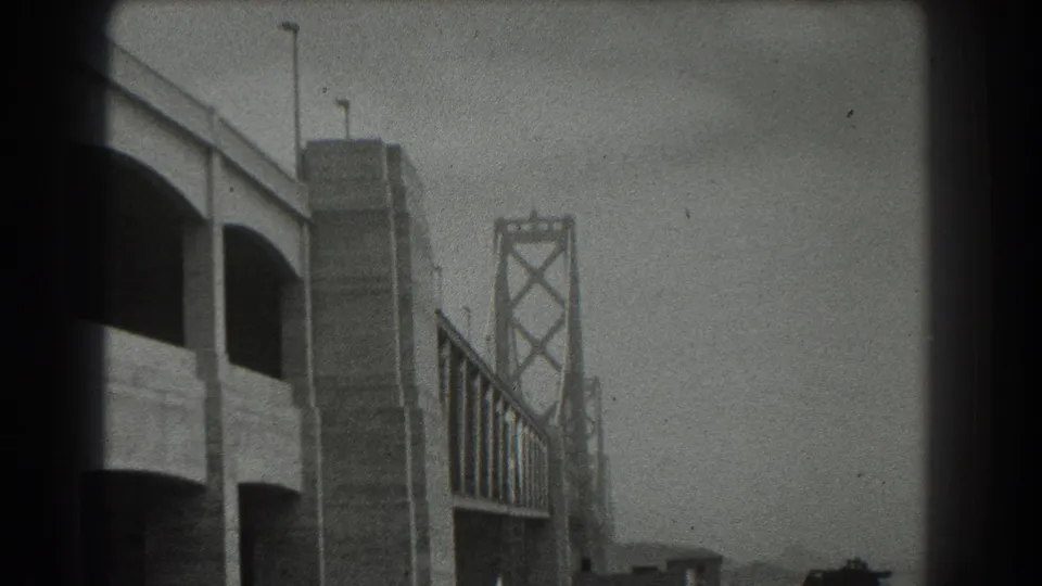 1939 San Francisco view of the Bay Bridge approach with tower structure, roadway supports, streetlights, and haze.