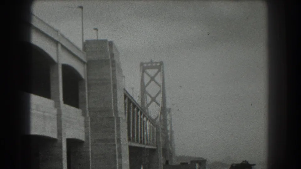 San Francisco Bay Bridge approach in 1939, framed close with concrete supports, tower truss, streetlights, and soft haze.