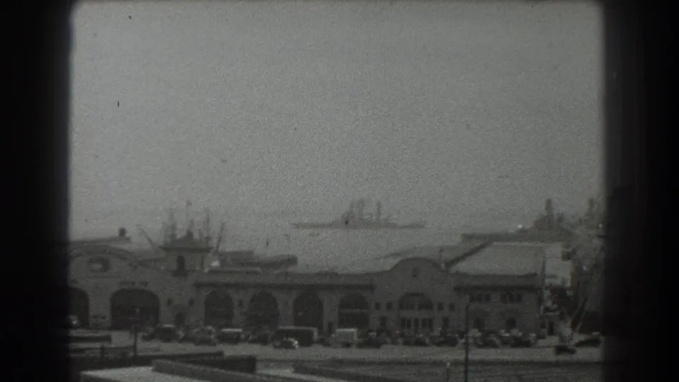 San Francisco harbor scene from 1939 showing an arched waterfront structure, cars along the curb, and vessels in the distance.