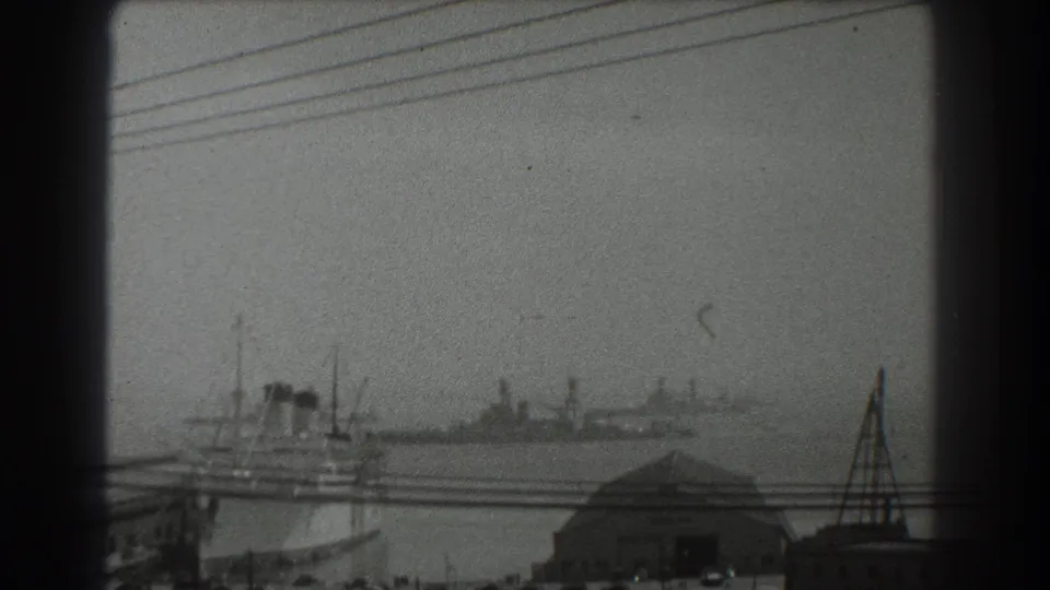 San Francisco harbor footage from 1939 showing ships and dock buildings through haze, crossed by utility wires and film scratches.