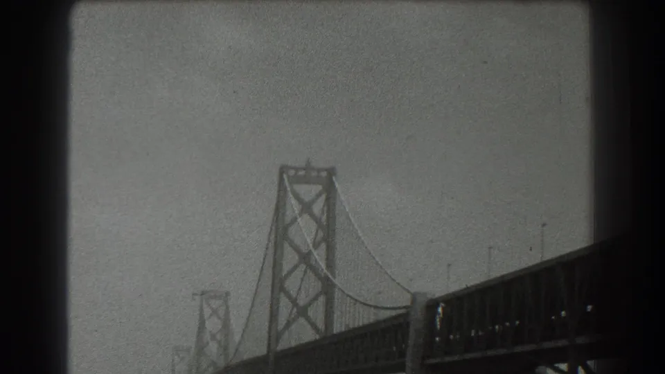 Black-and-white 1939 San Francisco bridge view with tower, cables, and deck receding through haze.