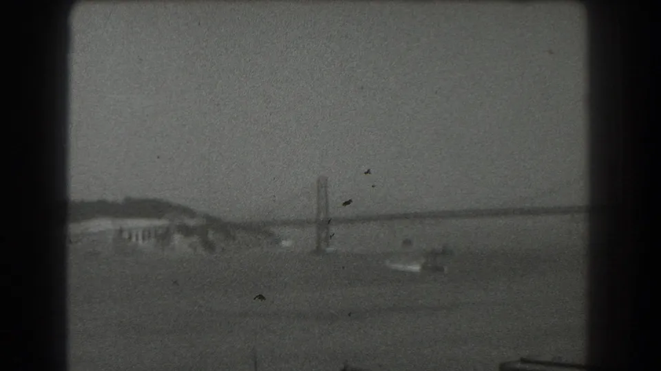 Wide 1939 San Francisco bay view showing a suspension bridge span, shoreline, water, and a small boat below.
