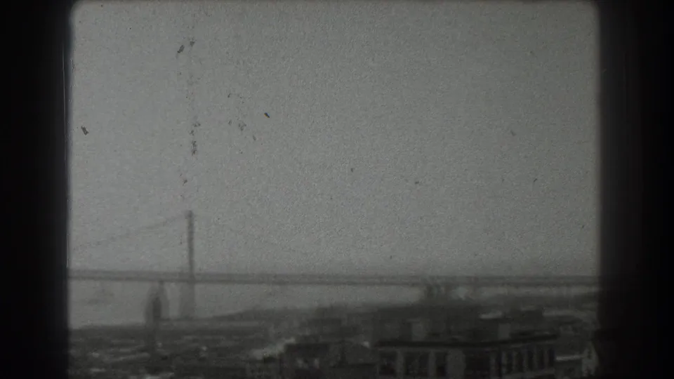 1939 San Francisco frame with a broad suspension bridge view, hazy bay water, and low waterfront buildings at the bottom edge.