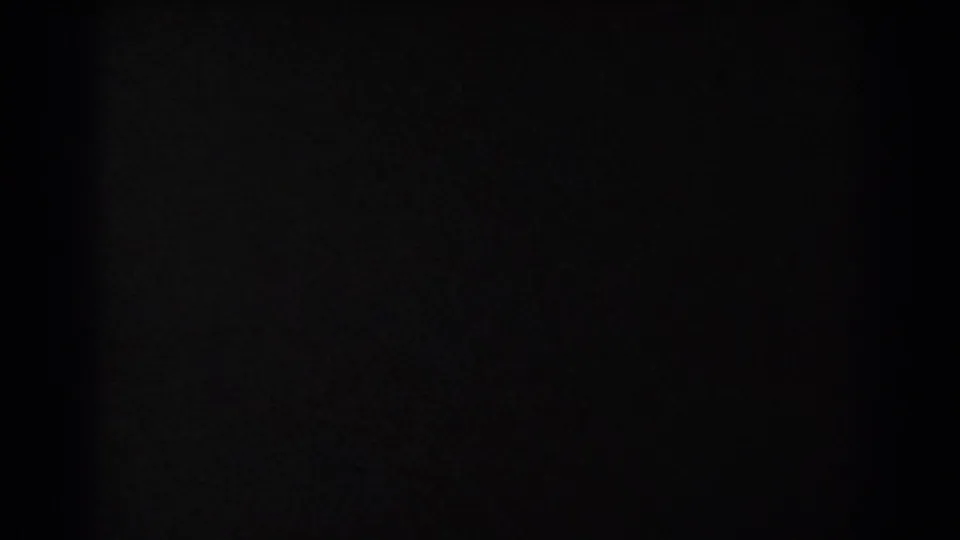 Underexposed 8mm frame from the San Francisco bridge view, with only faint dark shapes and film edges visible.