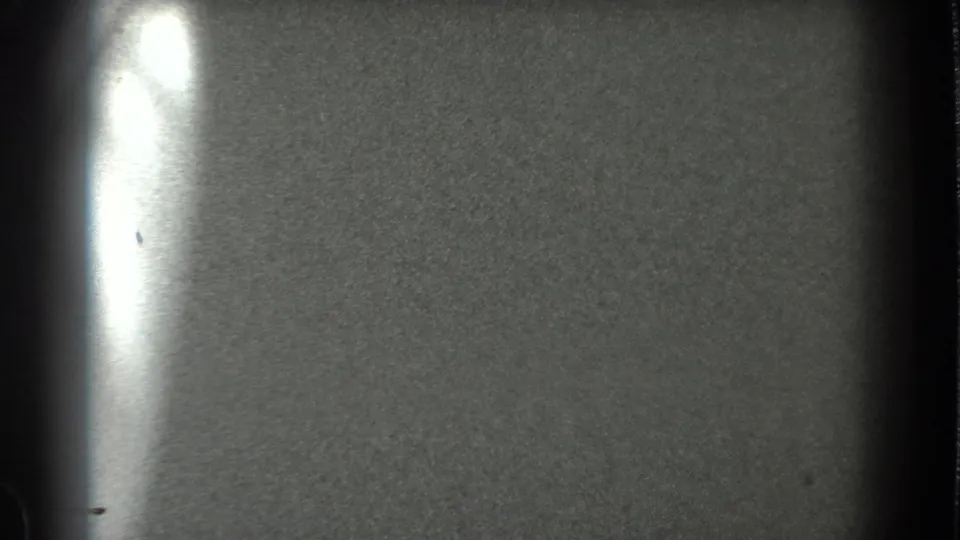 Grainy 8mm frame of the bay surface in the San Francisco clip, marked by a bright vertical film flare.