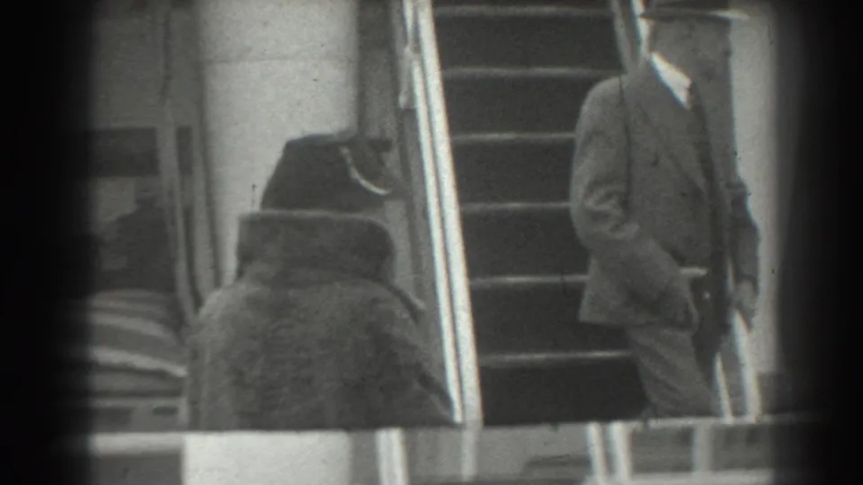 A well-dressed man in a suit and fedora stands beside broad steps and metal handrails in 1939 San Francisco home-movie footage.