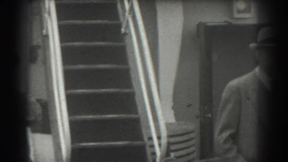 A 1939 San Francisco frame shows a metal-railed staircase, closed doorway, and a partially visible man in a hat.