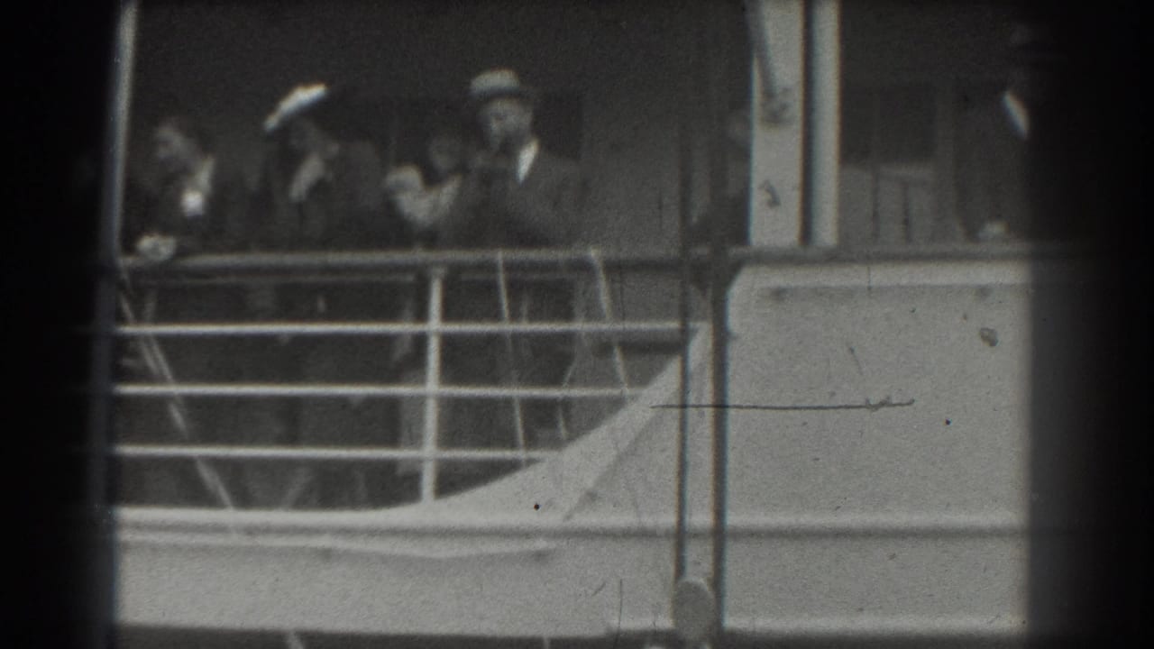 1939 San Francisco home-movie frame showing passengers in hats and suits behind railings on a ship deck.