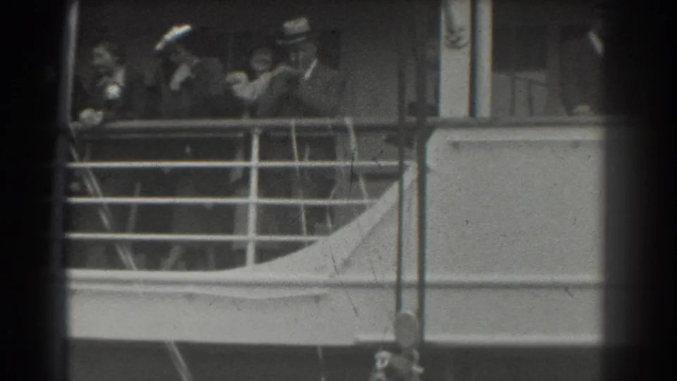 Passengers aboard a ship deck in 1939 San Francisco footage, with railings, windows, and period hats visible.