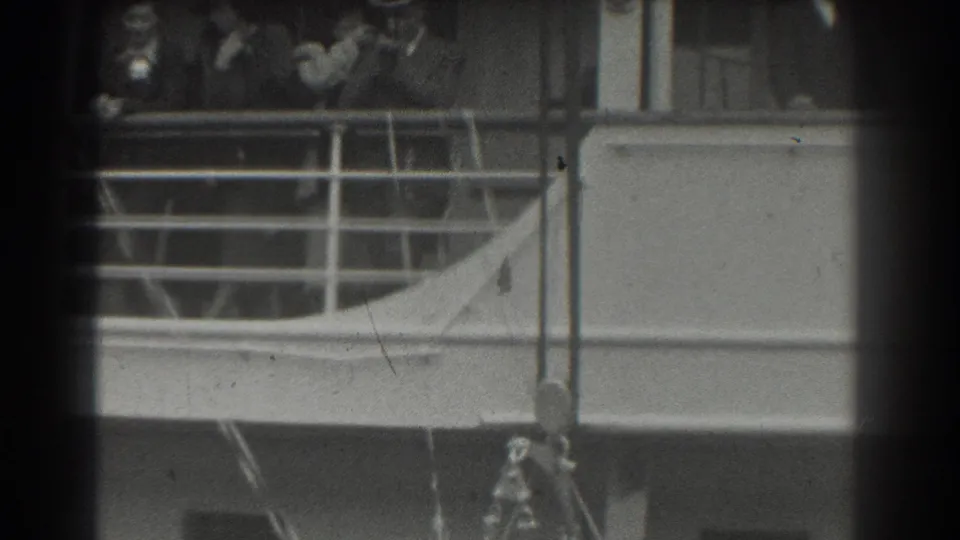 1939 San Francisco ship-deck home-movie frame with passengers in hats behind railings and vessel windows.