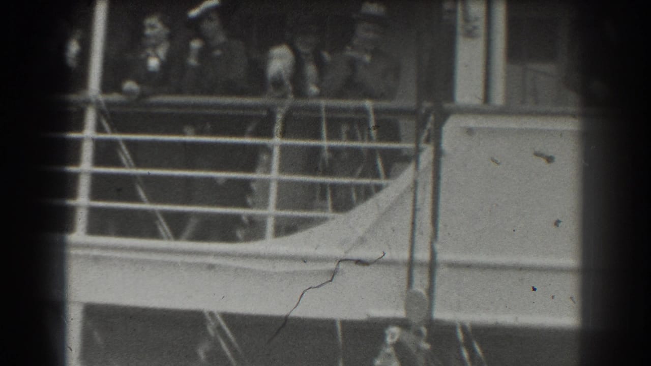 Distant ship deck with railings and several people partly visible behind dark film edges.