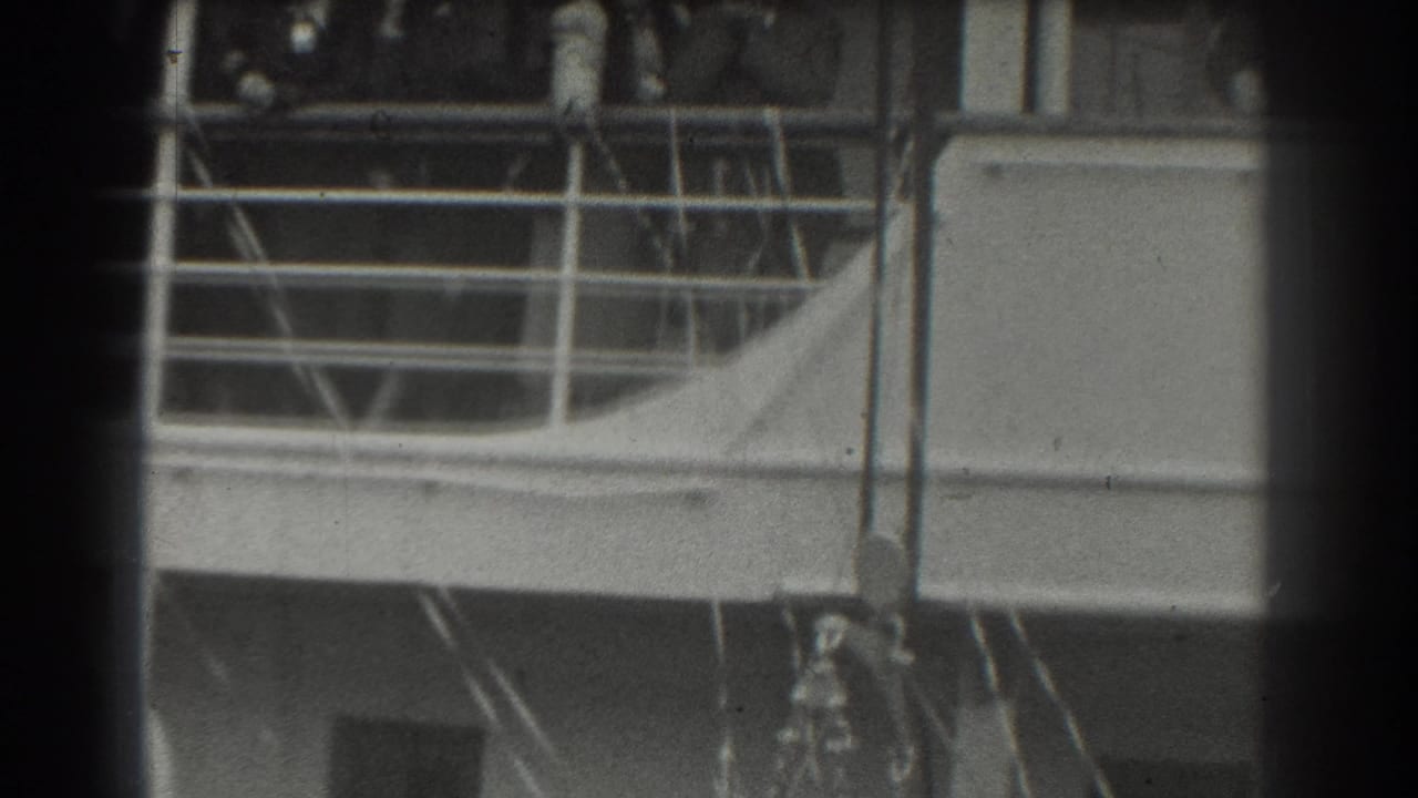 Ship deck railing and cabin area with indistinct people visible near the upper edge.