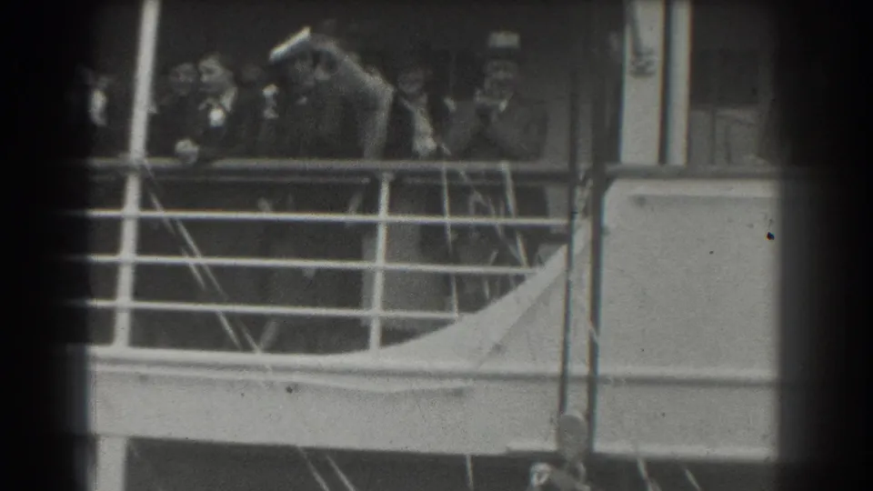 In 1939 San Francisco footage, well-dressed adults stand on a ship deck behind a metal railing, facing the camera area.