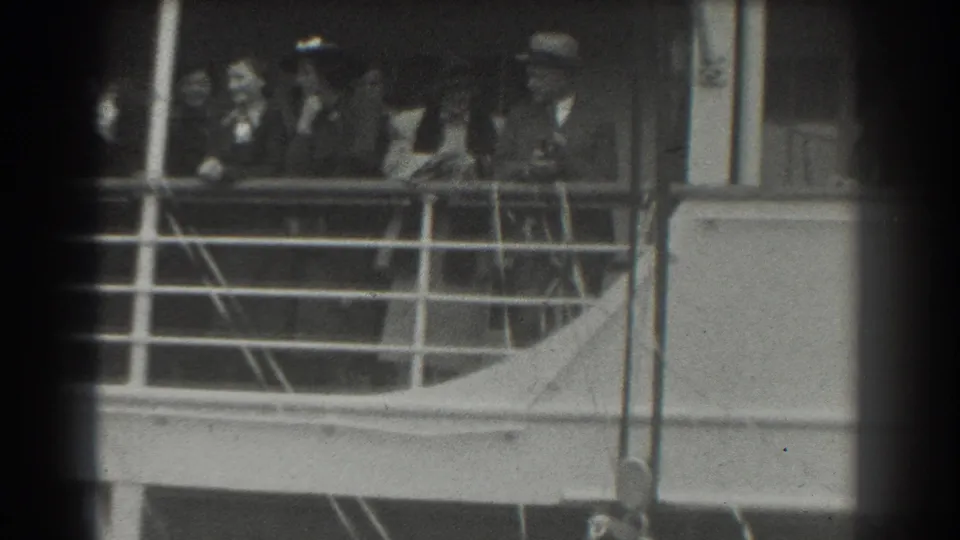 1939 San Francisco home-movie frame showing passengers in hats and coats gathered along a ship deck railing.