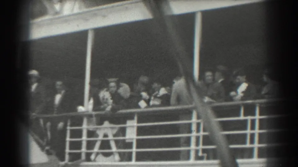 Passengers aboard a ship deck in the 1939 San Francisco clip, seen in formal coats and hats near railings and posts.