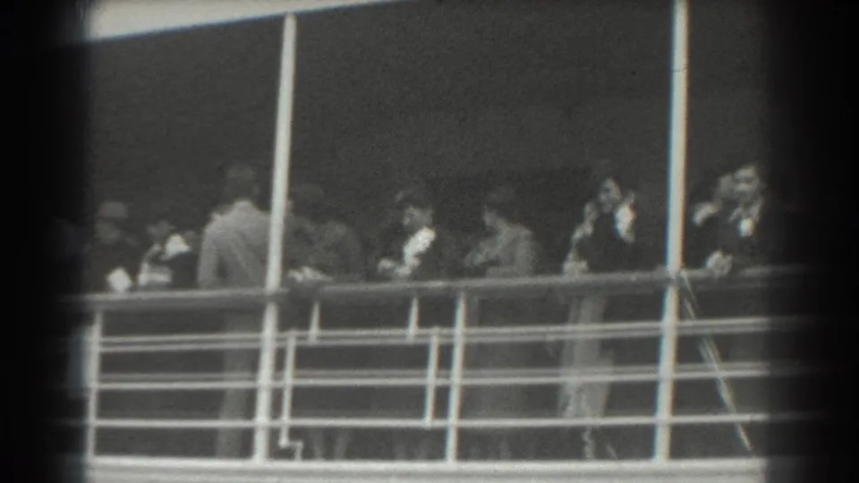 Adults in period clothing stand on a ship deck railing area in the listed 1939 San Francisco home-movie footage.