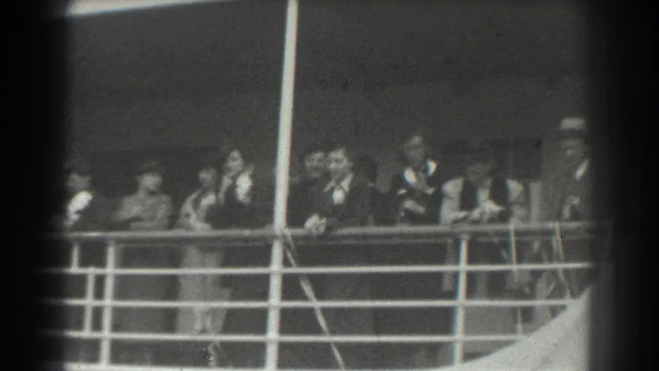 Passengers on a ship deck in the listed 1939 San Francisco footage stand beside railings, with a capped figure visible at right.