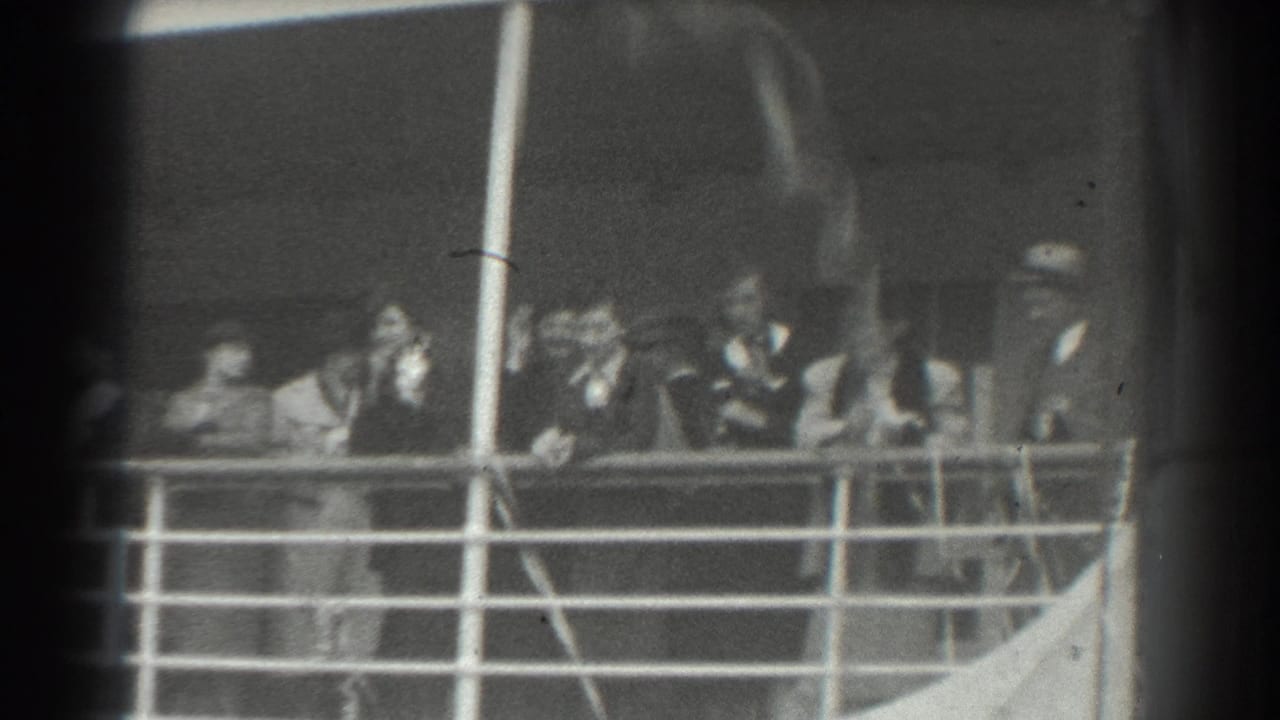Passengers standing behind a ship railing on an exterior deck.