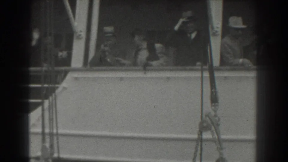 1939 San Francisco frame of passengers at a ship rail, including a man in a light hat and figures looking outward.