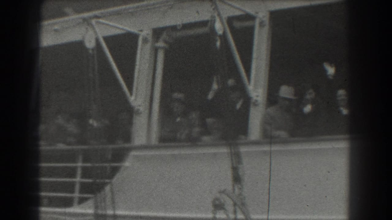 A group of passengers on a ship deck wave near white structural supports and railings.