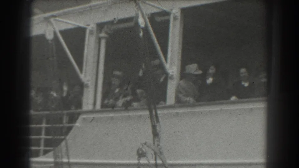 1939 San Francisco home-movie frame showing passengers in hats behind ship windows during a departure scene.