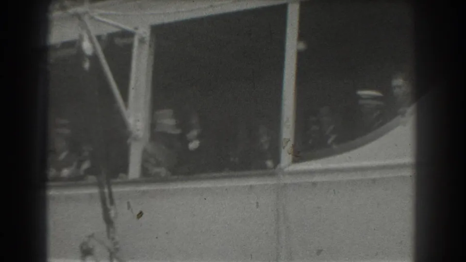 1939 San Francisco 8mm frame showing passengers looking from ship windows, with dark film edges and soft black-and-white detail.