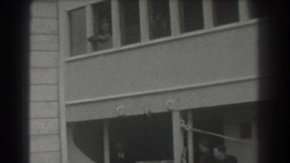 Black-and-white 8mm view of a ship exterior in San Francisco, showing windows above and a darker lower opening with faint figures.