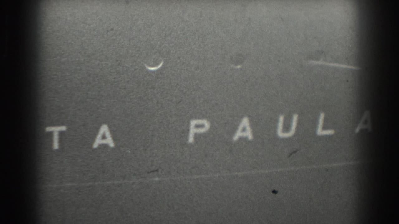 Partial white letters on a dark textured surface with visible film grain and edge vignetting.