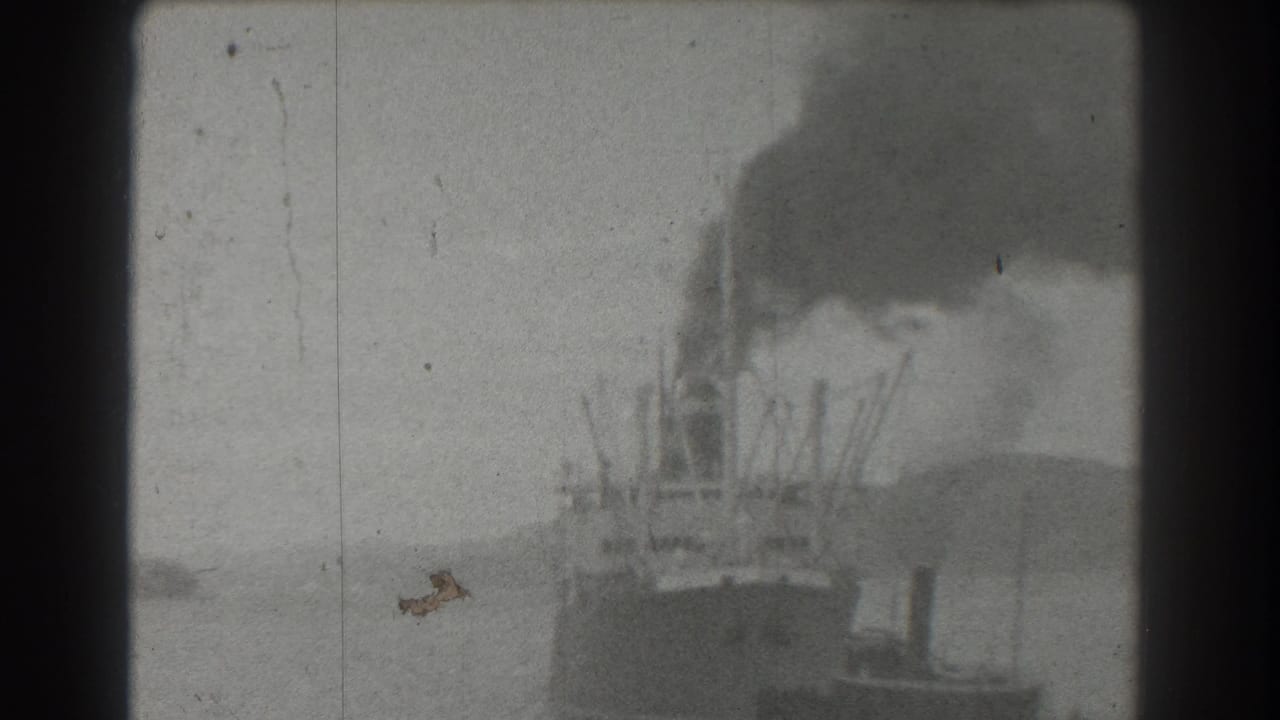 1939 San Francisco harbor footage shows a distant steamship or working vessel producing black smoke with a smaller tugboat near the waterline.