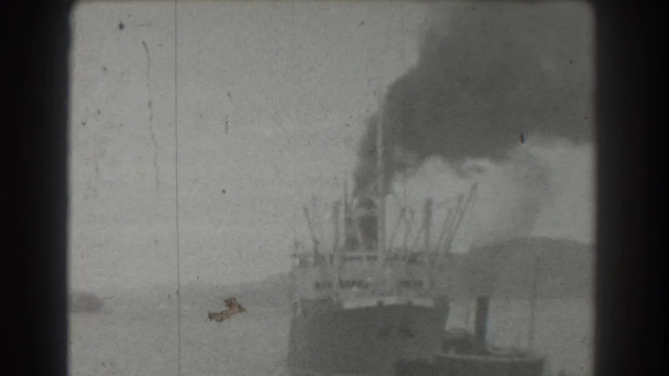 1939 San Francisco harbor footage shows a distant steamship or working vessel producing black smoke with a smaller tugboat near the waterline.