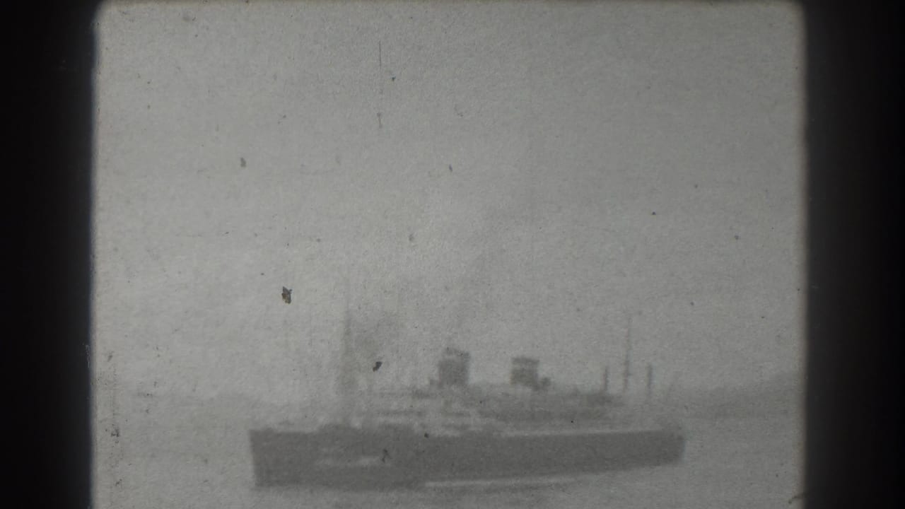 Black-and-white 1939 8mm frame of a distant steamship or ferry-like vessel on water near San Francisco, seen through soft focus and film grain.