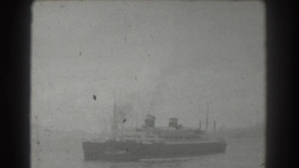 Black-and-white 1939 8mm frame of a distant steamship or ferry-like vessel on water near San Francisco, seen through soft focus and film grain.