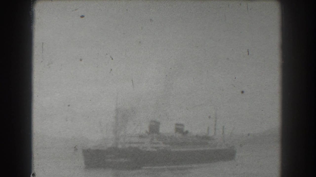 Vessel silhouette on water with smokestacks, masts, and hazy background.
