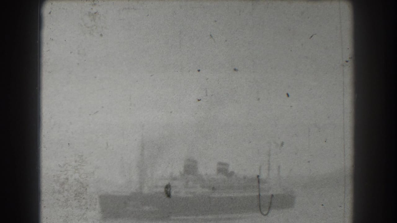 Distant large ship on hazy bay water with dark film borders and visible dust.