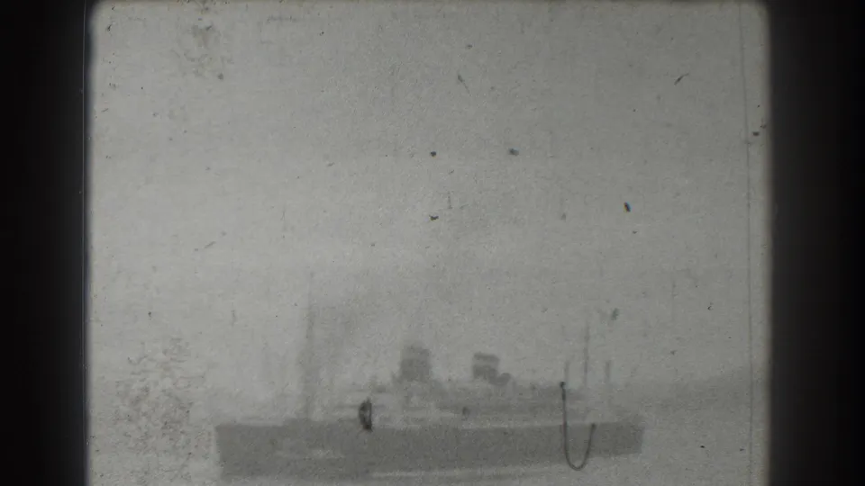 1939 8mm frame likely near San Francisco showing a large ship in a hazy bay, seen from a distant shore or waterfront viewpoint.