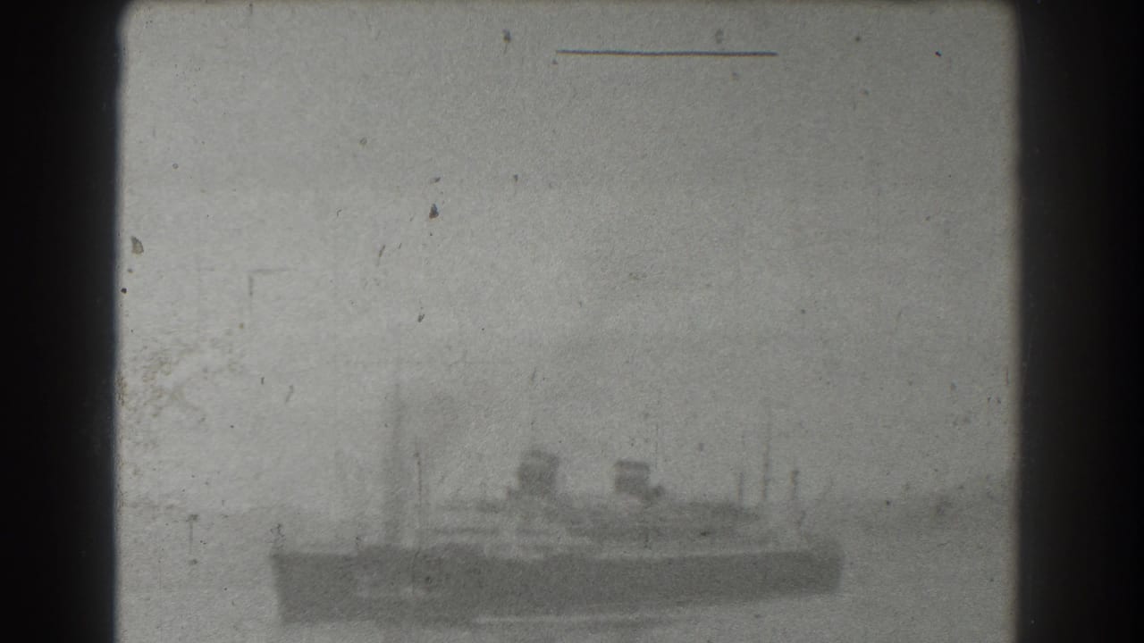 Large vessel seen from a distance through haze, with masts and funnels visible.