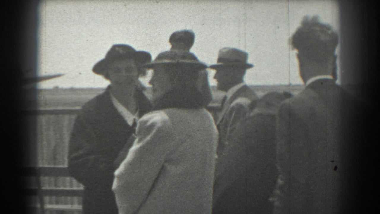 In 1939 San Francisco home-movie footage, adults in formal hats and coats stand together near a railing under a bright sky.