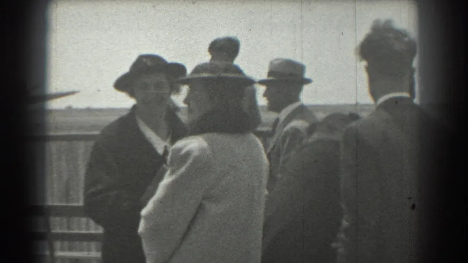 In 1939 San Francisco home-movie footage, adults in formal hats and coats stand together near a railing under a bright sky.