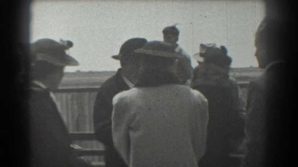 A candid 1939 San Francisco frame shows formally dressed adults clustered near a railing, some turned away from the camera.