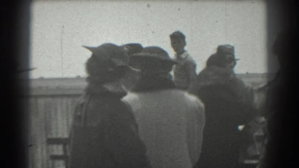 Adults in 1930s-style hats, coats, and suits stand in a loose group near a railing in San Francisco home-movie footage.