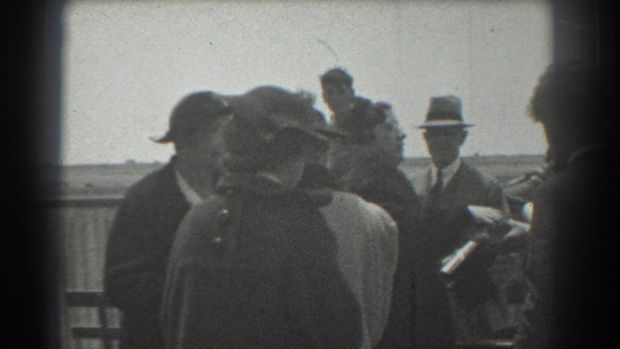1939 San Francisco 8mm frame showing adults in period hats and coats gathered on an outdoor platform near a railing.