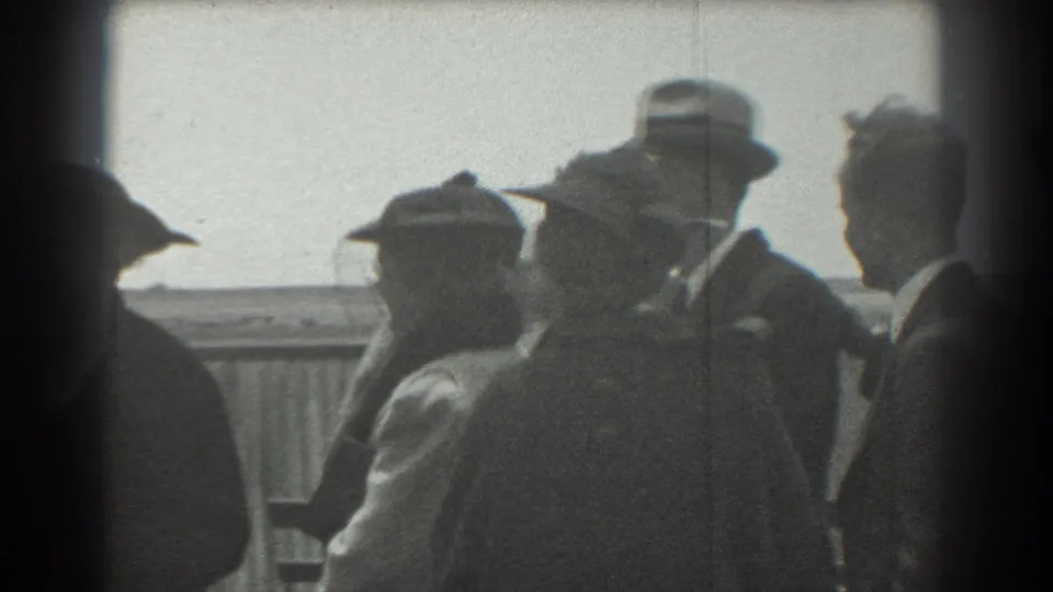 1939 San Francisco frame showing adults in hats and suits clustered near a railing on an outdoor platform.