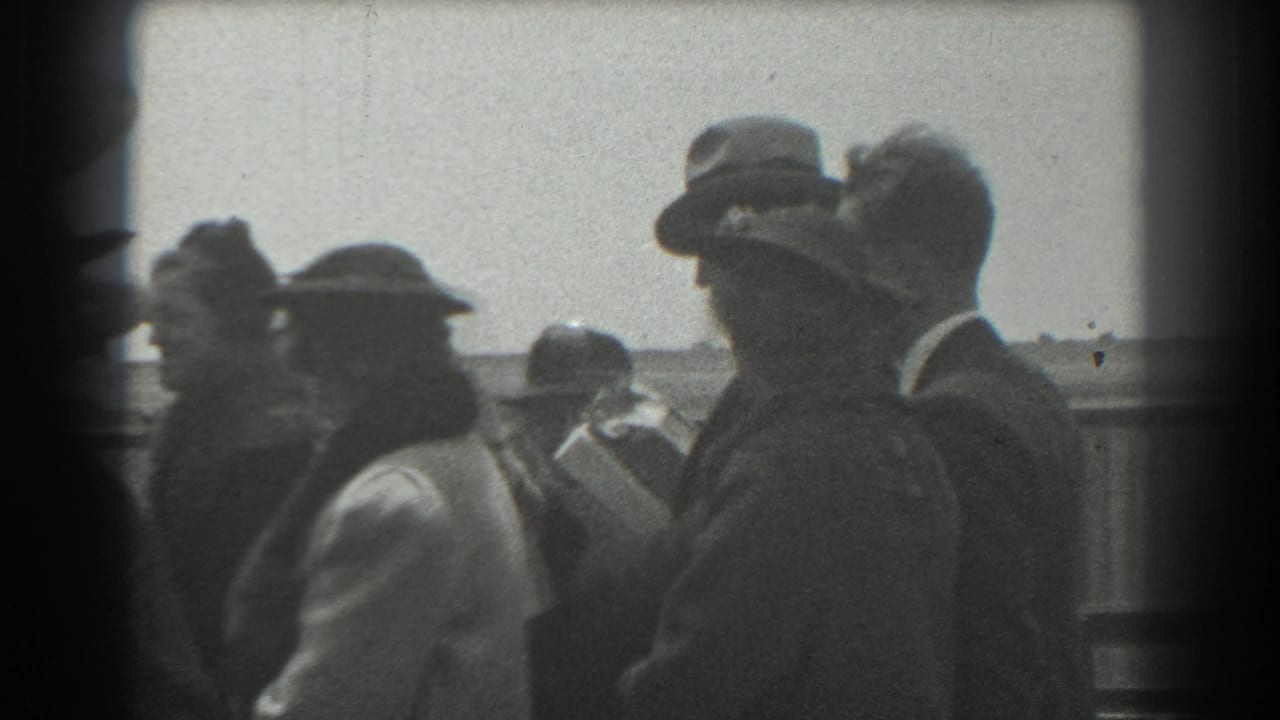Crowd members in hats and coats stand close together near a fence.