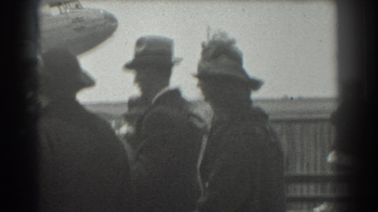 In 1939 San Francisco airport footage, suited adults and hat-wearing spectators stand near a barrier with a plane partly visible behind them.