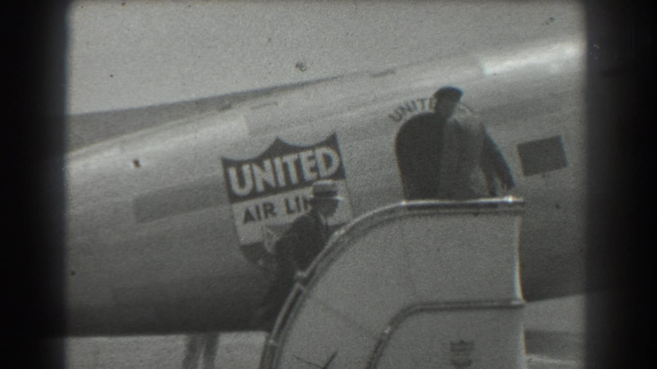 Person climbs exterior stairs beside a United Air Lines aircraft fuselage.