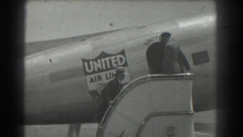 1939 San Francisco home-movie frame showing a person on exterior stairs beside a United Air Lines plane.